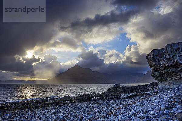 Schottische Küste mit Sonne  die durch die dramatischen Wolken über Loch Scavaig auf der Isle of Skye in Schottland  Vereinigtes Königreich  bricht