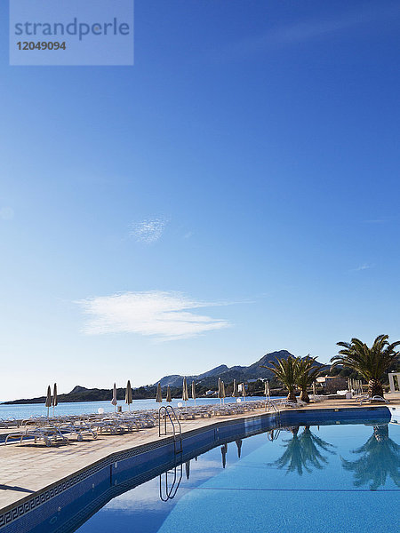 Sonnenliegen und geschlossene Sonnenschirme auf der Terrasse am Pool des Hotels  Cala Ratjada  Mallorca  Balearen  Spanien