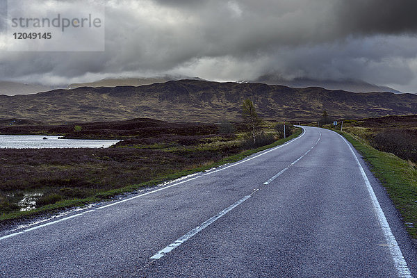 Landstraße durch Moorlandschaft mit Gewitterwolken im Rannoch Moor in Schottland  Vereinigtes Königreich