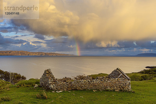 Überreste eines Steinhauses auf der Isle of Skye mit einem Regenbogen  der über der Küste in Schottland  Vereinigtes Königreich  erscheint