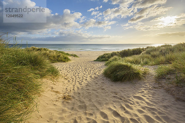 Fußabdrücke im Sand entlang eines Weges am Strand bei Sonnenaufgang  Nordsee in Bamburgh in Northumberland  England  Vereinigtes Königreich