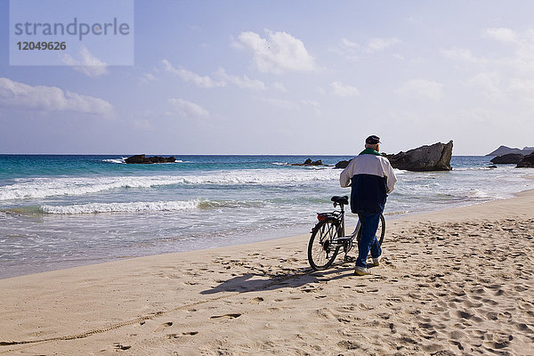 Mann mit Fahrrad am Strand