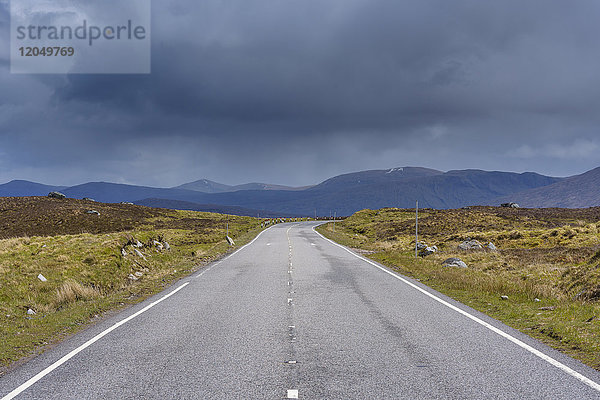 Landstraße mit dunkel bewölktem Himmel in den Highlands auf der A82 in Glen Coe  Schottland  Vereinigtes Königreich
