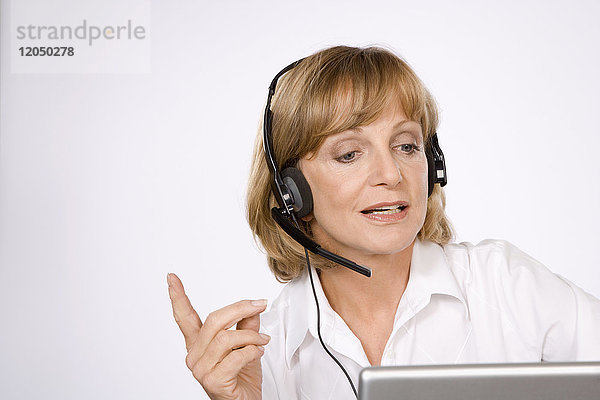 Geschäftsfrau mit Headset und Laptop-Computer