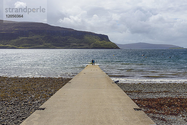Betonpier mit Paar mit Blick auf das Meer an einem sonnigen Tag auf der Isle of Skye in Schottland  Vereinigtes Königreich