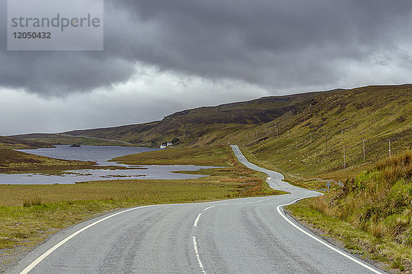 Kurvenreiche Küstenstraße und typisch schottische Landschaft auf der Halbinsel Trotternish auf der Isle of Skye in Schottland  Vereinigtes Königreich