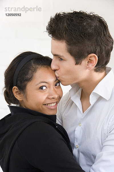 Mann küsst Frau auf Stirn