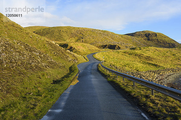 Typische schottische Landschaft auf der Isle of Sky mit einer Küstenstraße und grasbewachsenen Hügeln in Schottland  Vereinigtes Königreich