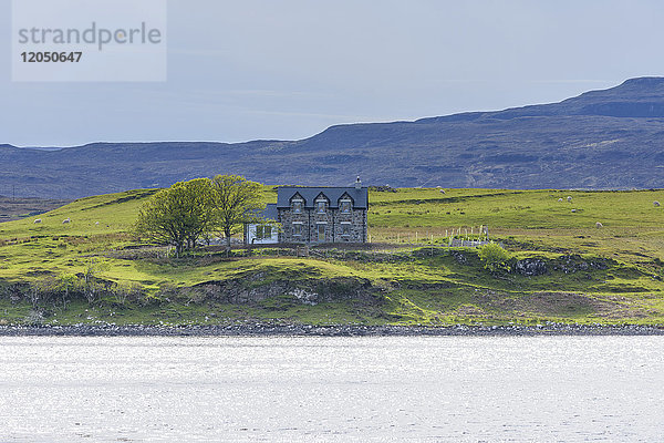 Meeresbucht mit typisch schottischem Wohnhaus in dem Dorf Dunvegan auf der Isle of Skye in Schottland  Vereinigtes Königreich