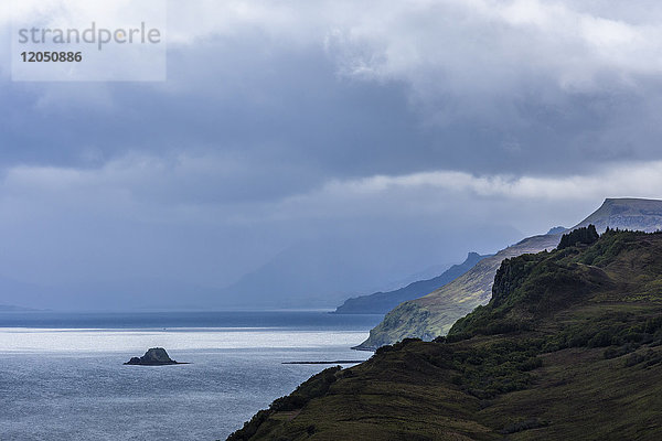 Sonnenbeschienener Ozean mit Meeresklippen und Regenwolken entlang der Küste der Isle of Skye in Schottland  Vereinigtes Königreich