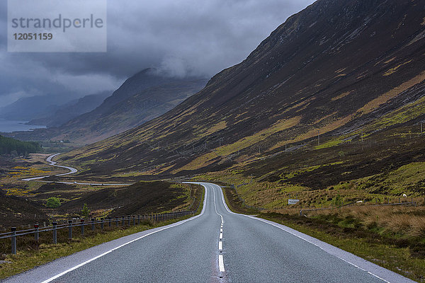 Gewitterwolken und typische schottische Landstraße durch die Highlands  Schottland  Vereinigtes Königreich