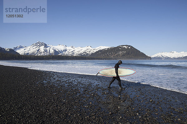 Surfer am Strand mit seinem Surfbrett  Kenai Peninsula Outer Coast  Süd-Zentral-Alaska  USA