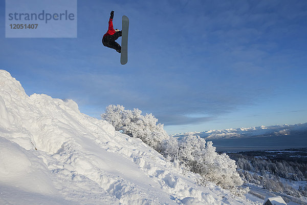 Snowboarder inmitten eines Sprungs an einem Berghang in Homer  Süd-Zentral-Alaska  USA