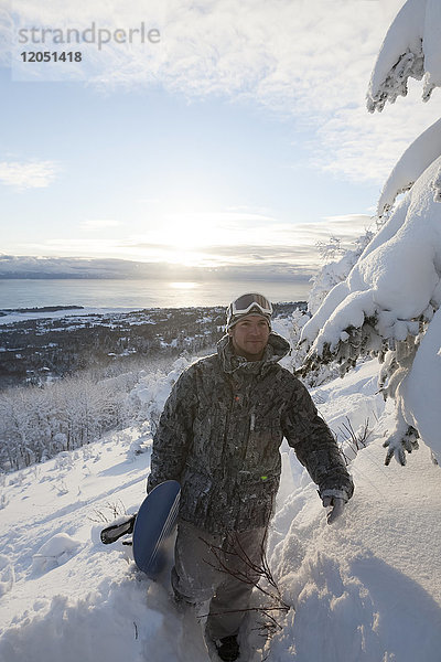 Snowboarder auf einem Hügel mit Blick auf die Kachemak Bay bei Sonnenuntergang  Homer  Southcentral Alaska  USA