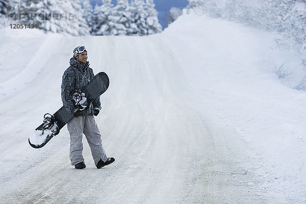 Snowboarder beim Überqueren einer schneebedeckten Straße  Homer  Southcentral Alaska  USA