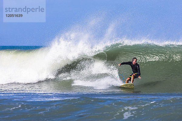 Ein Surfer reitet auf einer Welle am Pelican Beach am Atlantischen Ozean in Florida; Satellite Beach  Florida  Vereinigte Staaten von Amerika