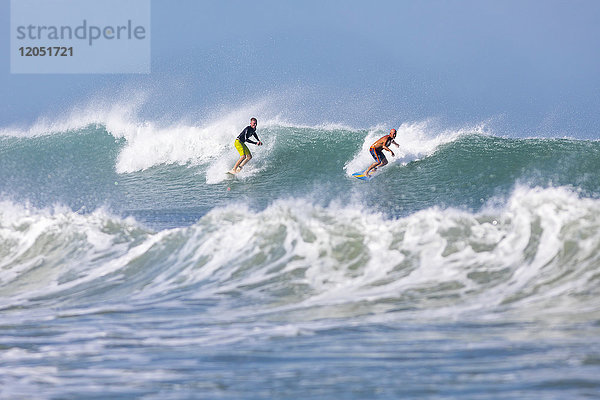 Ein Paar Surfer reitet auf einer Welle am Pelican Beach am Atlantischen Ozean; Satellite Beach  Florida  Vereinigte Staaten von Amerika