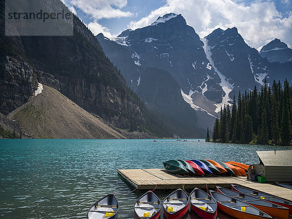 Kanus im Wasser und auf einem Steg sitzend am Ufer des Moraine Lake in den kanadischen Rocky Mountains; Eldon  Alberta  Kanada