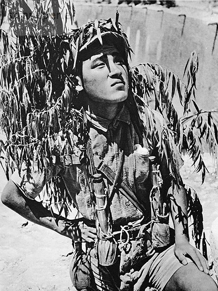 Die Illustrated London News 1941. Zweiter Weltkrieg. Im Chinesisch-Japanischen Krieg ein junger chinesischer Soldat mit Granaten bewaffnet und getarnt vor der Zitadelle von Tungkwan am Gelben Fluss