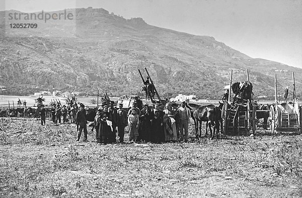 Ein Vintage-Schwarz-Weiß-Bild von einer großen Gruppe von Menschen mit ihren Pferden und Kutschen stehen