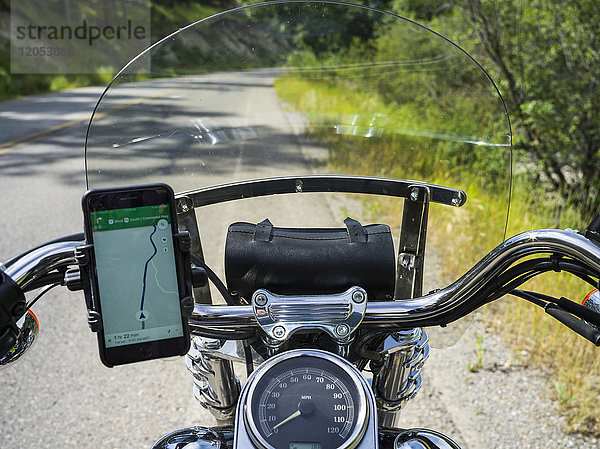 Ein Motorrad am Straßenrand mit einem Smartphone in einer Halterung am Lenker zur Anzeige der Karte während der Fahrt; Kimberley  British Columbia  Kanada