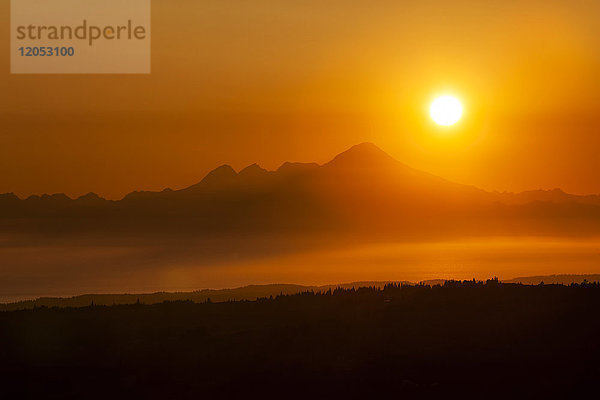 Glühende Sonne während eines goldenen und orangefarbenen Sonnenuntergangs über den Kenai Mountains  Kachemak Bay State Park; Alaska  Vereinigte Staaten von Amerika