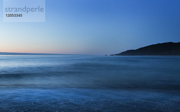 Meereslandschaft bei Sonnenuntergang mit klarem  blauem Himmel und ruhigem Meerwasser  Karamea Strand; Südinsel  Neuseeland