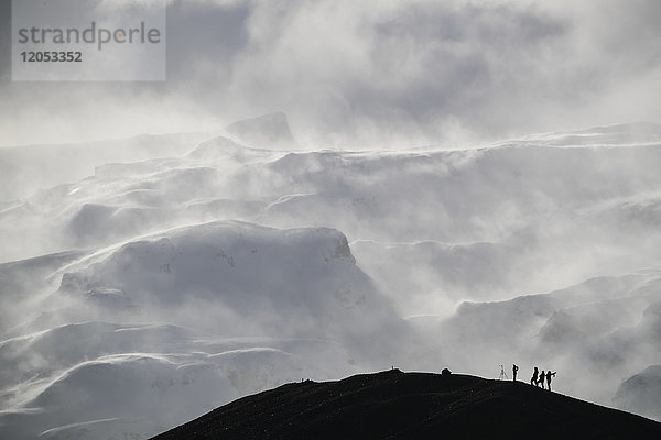 Gruppe von Fotografen Silhouette gegen den Schnee beladenen Berg; Island