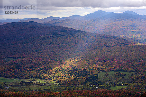 Ein Sonnenstrahl scheint durch die Wolken auf den herbstlich gefärbten Wald unter uns; Dunham  Quebec  Kanada