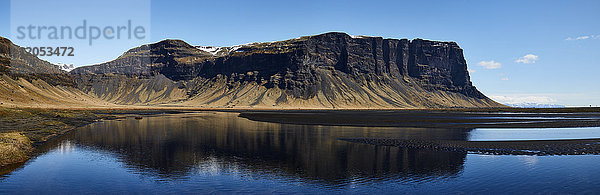 Zerklüftete Klippen  die sich im ruhigen Wasser spiegeln; Island