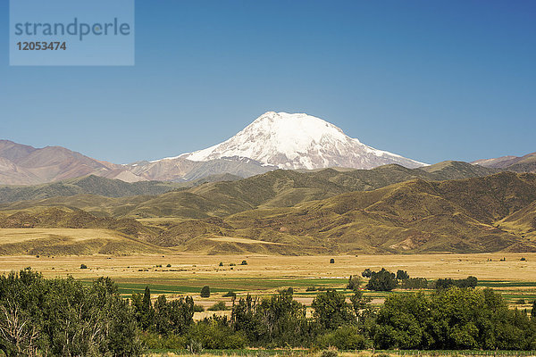 Ein schneebedeckter Vulkan ragt über die Ausläufer der Anden und das Ackerland; Mendoza  Argentinien