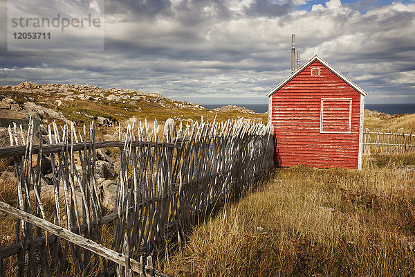 Ein kleiner roter Schuppen neben einem hölzernen Lattenzaun an der Küste; Neufundland  Kanada