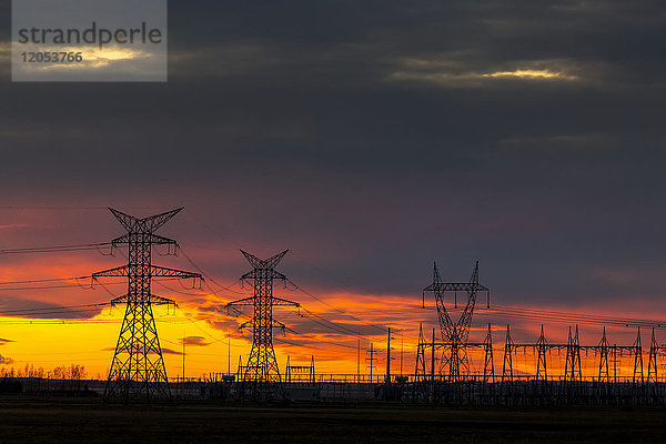 Silhouette von großen elektrischen Metalltürmen bei Sonnenuntergang mit einem bunten Himmel im Hintergrund; Calgary  Alberta  Kanada