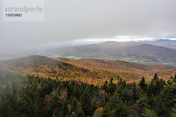 Regen fällt aus schweren Wolken über einem herbstlich gefärbten Wald in den Bergen; Dunham  Quebec  Kanada