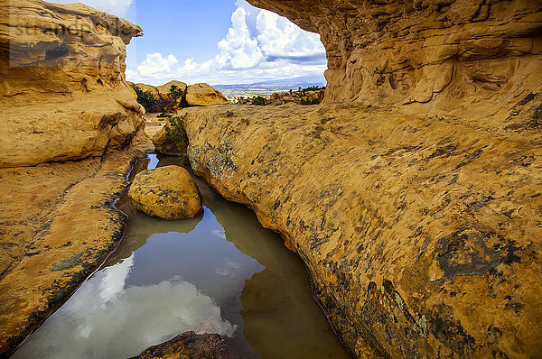 Von Felsen eingeschlossenes Wasserbecken  in dem sich Himmel und Wolken spiegeln  im El Malpais National Monument in der Nähe von Grants  New Mexico im Frühherbst; New Mexico  Vereinigte Staaten von Amerika