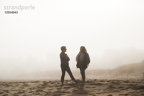 Zwei Freundinnen stehen im Gespräch an einem Strand im Nebel; Prince Edward Island  Kanada