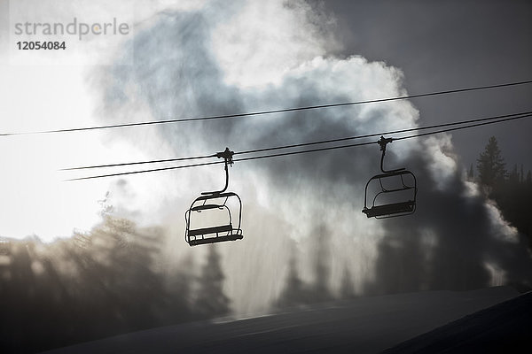 Silhouette eines Sessellifts auf einem Skihügel mit künstlichem Schnee aus einer Schneekanone im Gegenlicht des Sonnenlichts  Copper Mountain Resort; Colorado  Vereinigte Staaten von Amerika