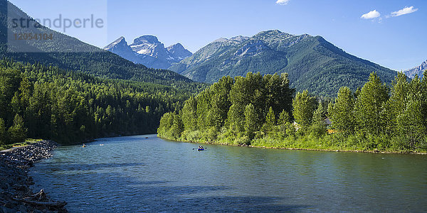 Kanufahrer auf dem Elk River mit den zerklüfteten kanadischen Rocky Mountains in der Ferne; Sparwood  British Columbia  Kanada