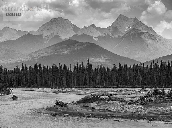 Schwarz-Weiß-Landschaft der zerklüfteten kanadischen Felsenberge mit einem Wald und einem fließenden Fluss im Vordergrund; Invermere  British Columbia  Kanada