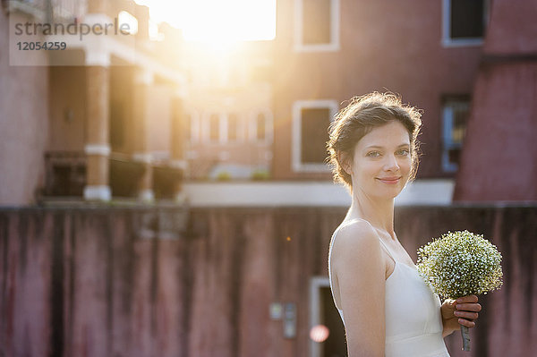 Italien  Venedig  Porträt der lächelnden Braut mit Brautstrauß bei Sonnenaufgang