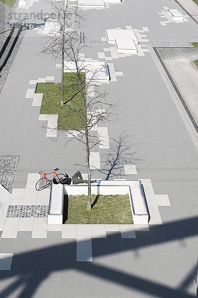Mann entspannt im City-Skatepark mit Smartphone neben dem Fahrrad