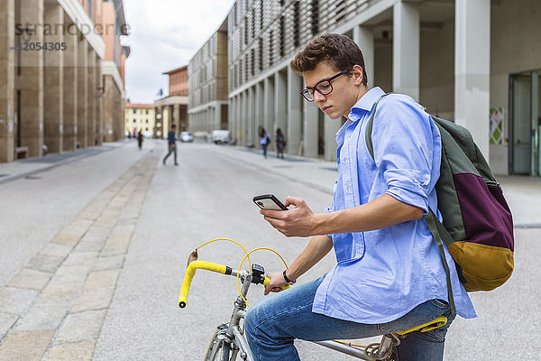 Junger Mann auf dem Rennrad beim Blick aufs Handy
