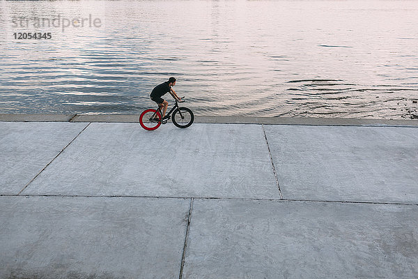 Junger Mann auf Fixie Bike am Wasser