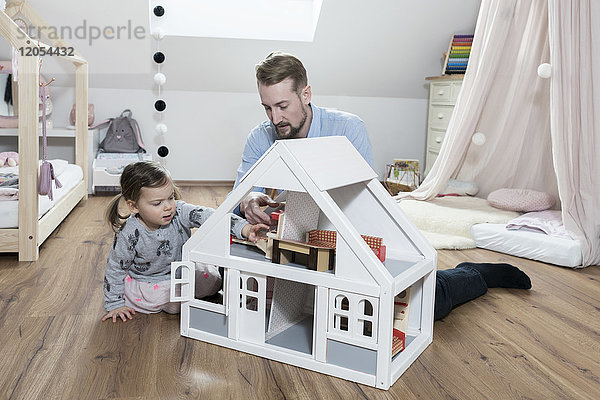 Vater und Tochter spielen mit Puppenhaus in ihrem Kinderzimmer