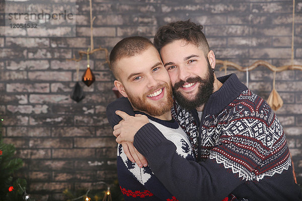 Porträt eines glücklichen schwulen Paares  das sich zu Weihnachten umarmt