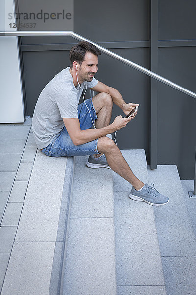 Mann auf der Treppe sitzend  mit Smartphone