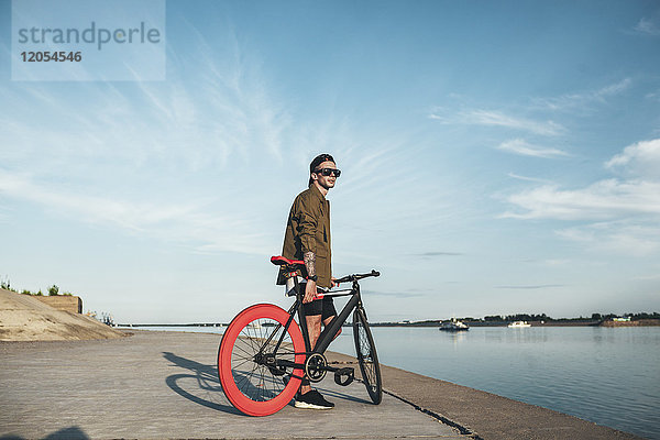 Junger Mann mit Fixie Bike am Wasser
