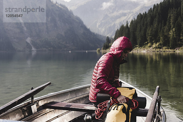 Österreich  Tirol  Alpen  Frau mit Rucksack im Boot auf dem Bergsee