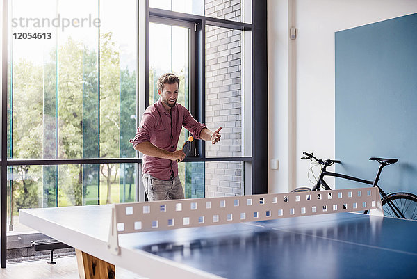 Mann im Pausenraum des modernen Büros beim Tischtennisspielen