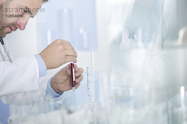 Mann untersucht Reagenzglas mit Flüssigkeit im Labor